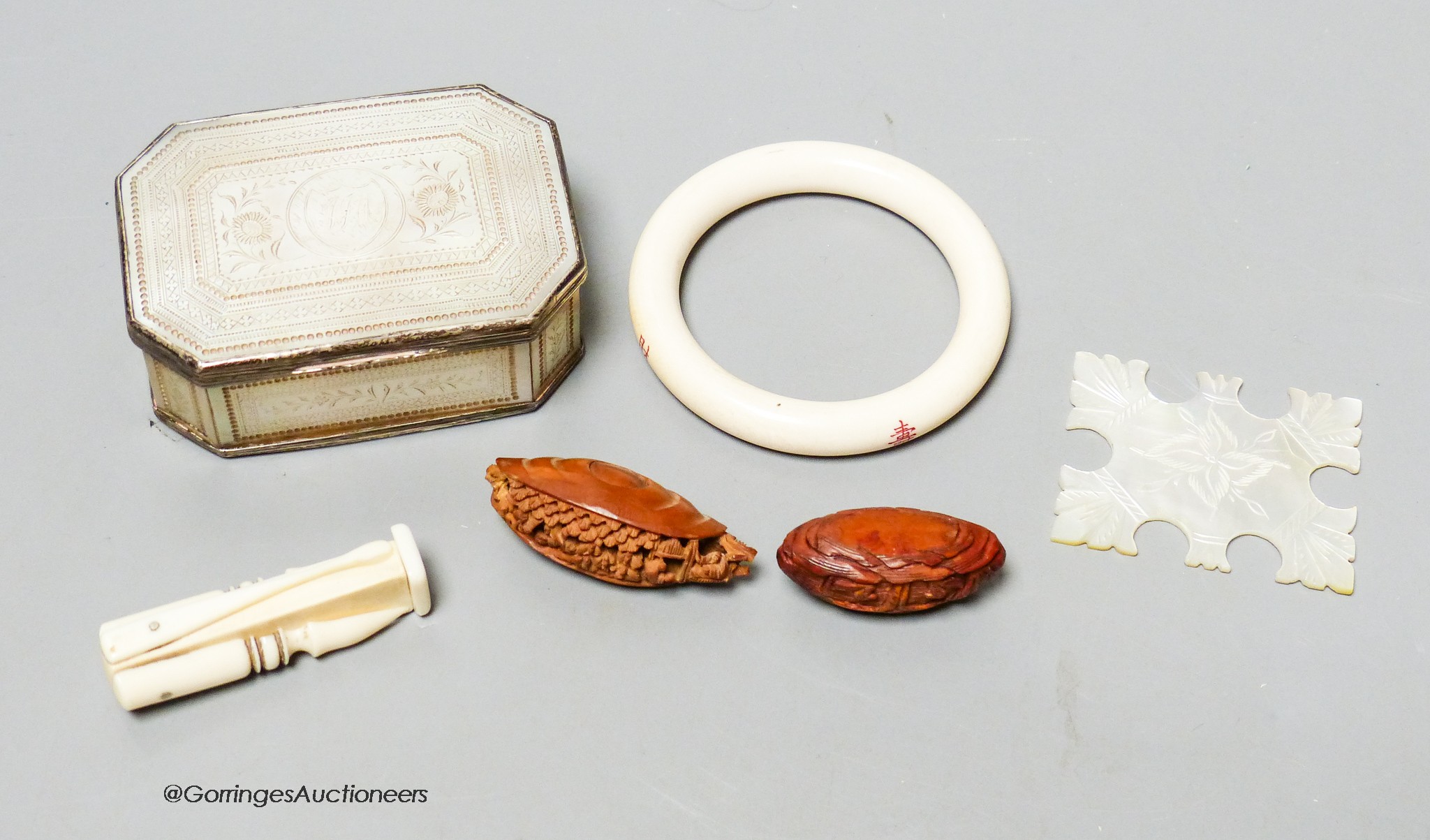 A 19th century panelled mother of pearl box together with a Chinese carved peach stone, a Chinese ivory bangle and a small worked bone multi-tool